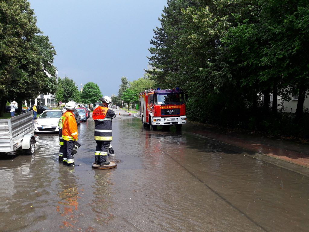 Mitten im neu gebildeten See auf der Robert-Koch-Straße hat die Feuerwehr den Sickerschachteinlauf gefunden und den Deckel herausgehoben.